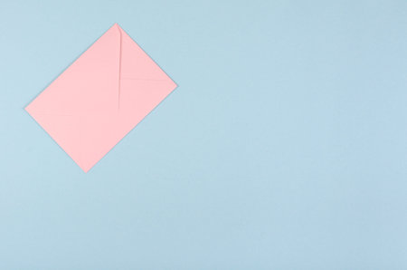 Pink paper envelope composition on blue background. Flat lay, layout and tabletop mockup with copy...