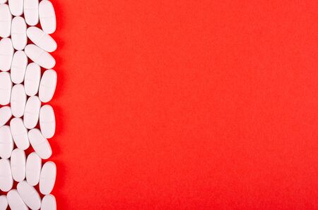 White medical pills composition on red background. Flat lay, layout and tabletop mockup with copy space.の写真素材