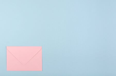 Pink paper envelope composition on blue background. Flat lay, layout and tabletop mockup with copy space.の写真素材