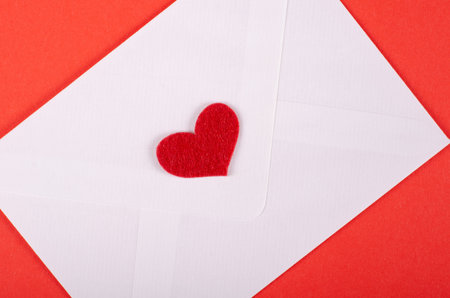 Paper envelope with heart composition on red background. Flat lay, layout and tabletop mockup with...
