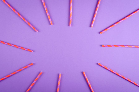 Colored drinking straws composition on purple background, party and celebration decoration. Flat...
