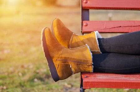 Girls legs in brown shoes lie on a wooden bench. Sunshine.の写真素材