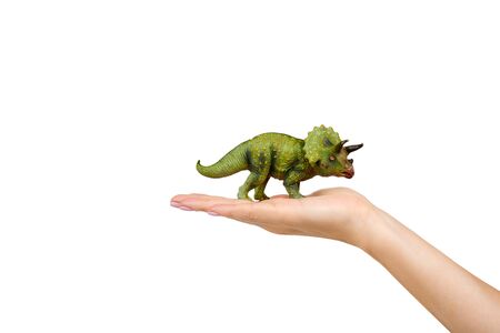 Green rubber dinosaur toy with hand, prehistoric wild animal. Isolated on white background. Copy space.の写真素材
