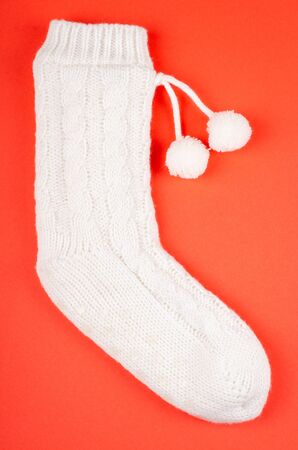 White socks with pom poms on red background composition. Flat lay and top view photo with copy space.の写真素材