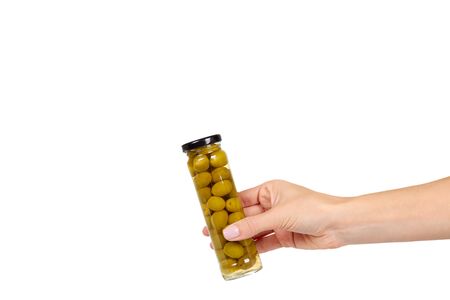 Hand with glass jar with green olives. Canning supply food. Isolated on white background. Copy space.の写真素材