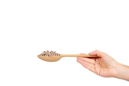 Hand with loop cereal, breakfast food. Crunchy snack with oat and corn. Wooden spoon. Isolated on white background. Copy space.の写真素材