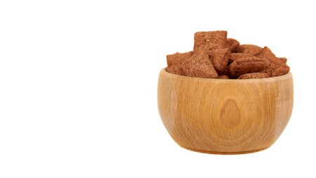 Chocolate pillow cereal, breakfast food. Crunchy snack with oat and corn. Wooden bowl. Isolated on white background. Copy space.の写真素材