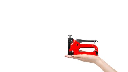 Hand with red industrial stapler, furniture industry hardware. Isolated on white background. Copy space, template.の写真素材