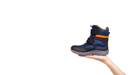 Hand with blue and orange kids boots. Isolated on white background. Copy space, template.