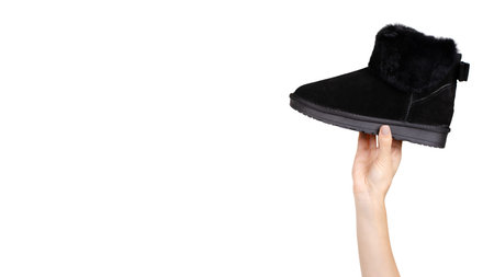 Hand with black leather female shoes. Isolated on white background. Copy space, template.