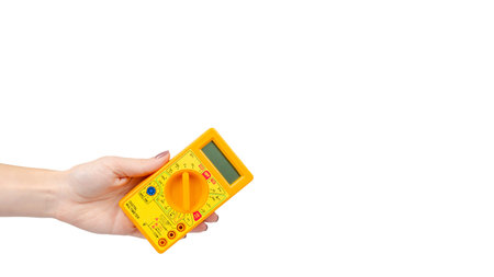 Hand with yellow plastic multimeter, electric tester tool. Isolated on white background. Copy space,...