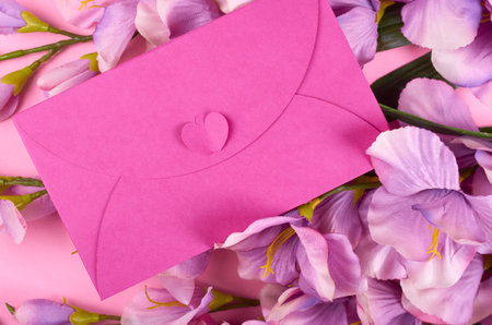 Envelope and flowers on pink background composition. Flat lay photo.