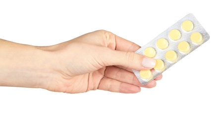Yellow pills in blister with hand. Isolated on white background.