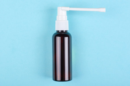 Throat spray bottle on blue background. Flat lay, overhead view image. Copy space, template.