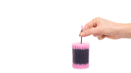 Hand with black and pink ear stick cleaner. Isolated on white backgorund. Copy space, template.