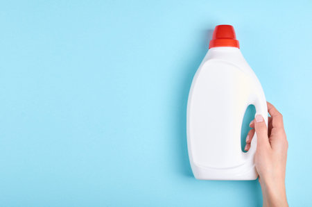 Hand with white detergent bottle, washing soap, cleaning gel. Flat lay, overhead view image. Copy...