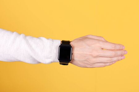 Black smart watch on hand on yellow background.の写真素材
