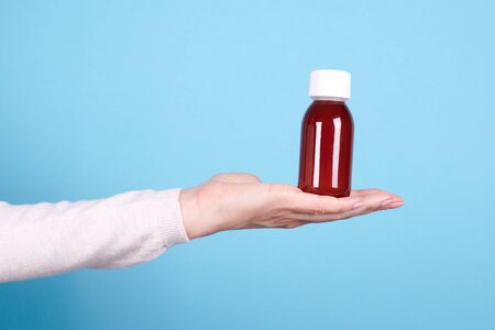 Antipyretic bottle in hand on blue background.の写真素材