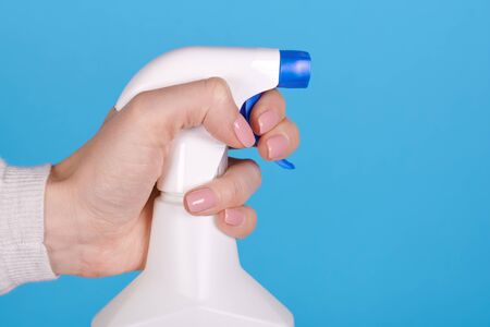 Cleaning spray bottle in hand on blue background. Close up photo.の写真素材