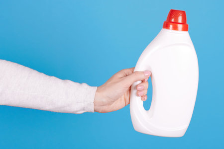 White bottle with liquid detergent in hand on blue background.の写真素材