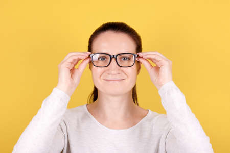 Portrait of a brunette girl puts on glasses. Isolated on pink background.の写真素材