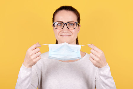 Portrait of a brunette girl in eyeglasses, puts on a medical mask.