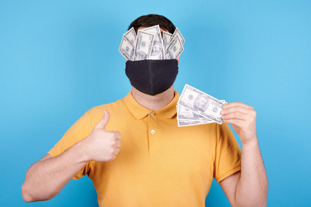 Brunette man in protection mask, paper money on the face.