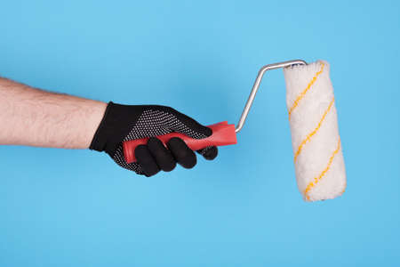 Hand in working glove with paint roller.の写真素材