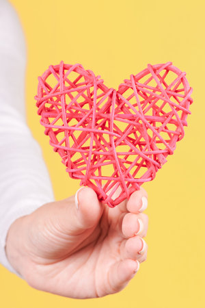 Hand with red wooden heart decoration.