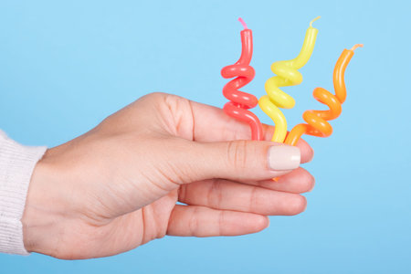 Hand with colored birthday candles.