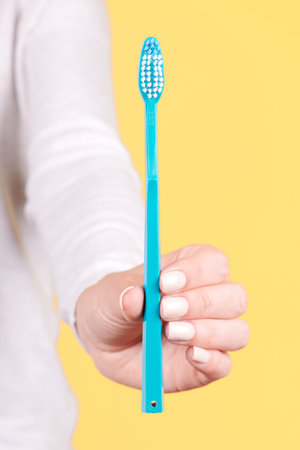 Hand with blue toothbrush, dental care.