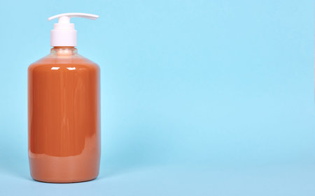 Orange liquid soap bottle, plastic dispenser.