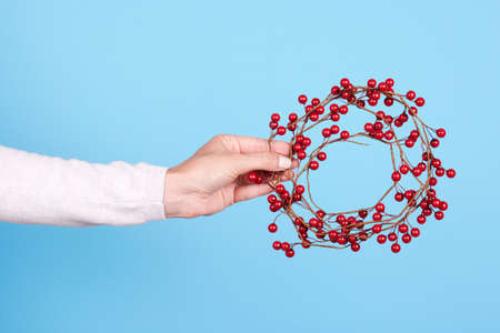 Hand with red berries wreath, christmas decoration.の写真素材