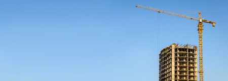 Unfinished construction of high-rise building with cranes.