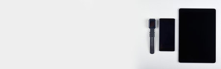 Different mobile gadgets, cellphone, tablet and smart watches on grey background.