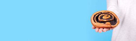 Handmade roll with poppy seed in hand.の写真素材