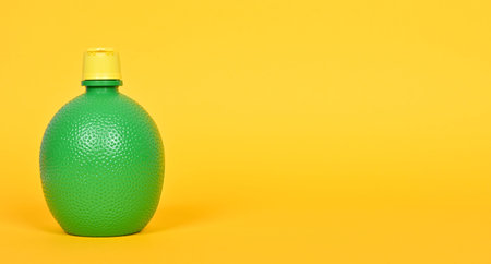 Concentrate lemon juice in a green bottle on a yellow background.