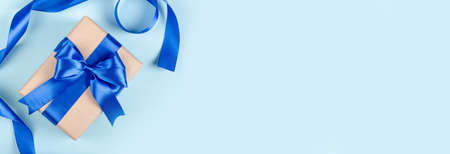 Gift box on blue background composition, present with ribbon and bow. Flat lay and top view photo with copy space.の写真素材