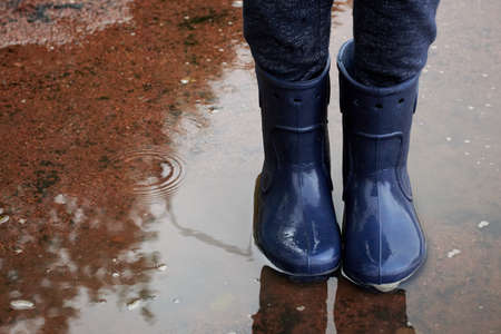 Childs legs in boots stand in puddle.の写真素材