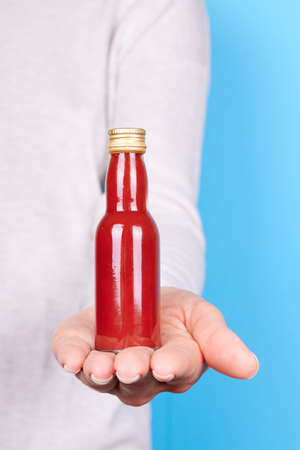 Hand with red hot sauce in bottle.の写真素材