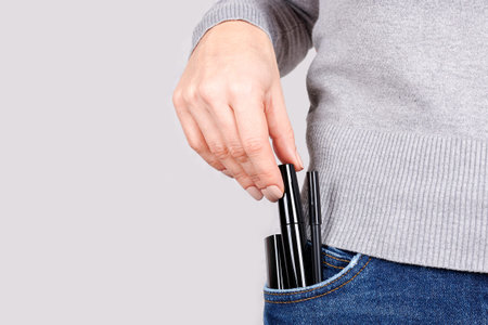 Makeup objects in jeans pocket on grey.