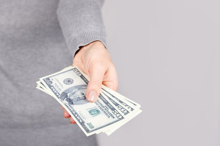 Hand with dollar cash on grey.