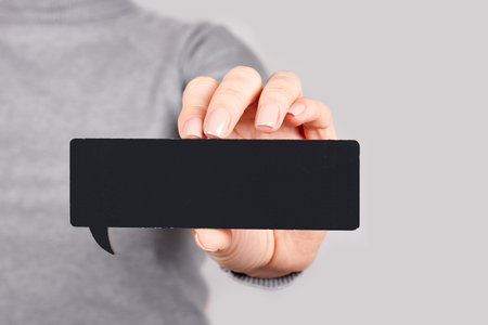 Hand with black wooden signboard on grey.の写真素材