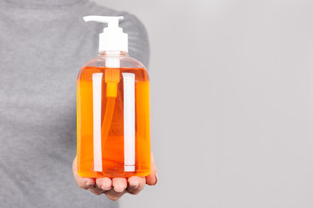Hand with liquid soap dispencer on grey.の写真素材