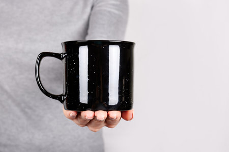 Hand with black cup on grey.の写真素材