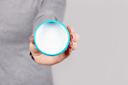 Hand with blue jar on grey.の写真素材
