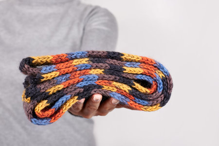 Hand with wool scarf on grey.