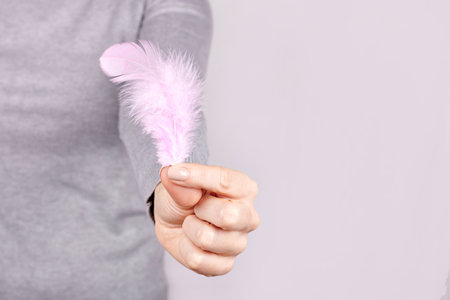 Hand with purple feather on grey.の写真素材
