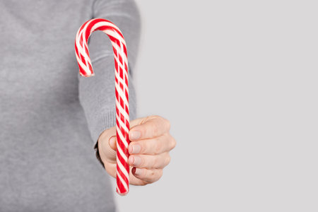 Hand with red striped candy on grey.の写真素材