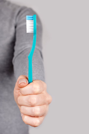 Hand with blue toothbrush on grey.の写真素材